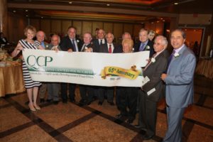 QCP Board of Directors holding up the 65th Anniversary sign kicking off our 65th Year of Helping People with Developmental Disabilities.